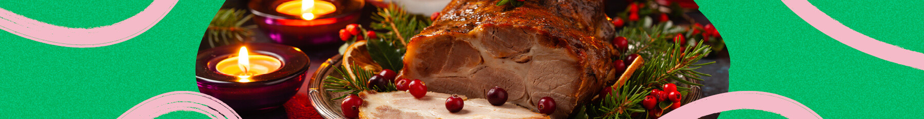Roast pork neck in Christmas style. Dark navy blue background. Christmas accessories. Candles and lanterns in the background.