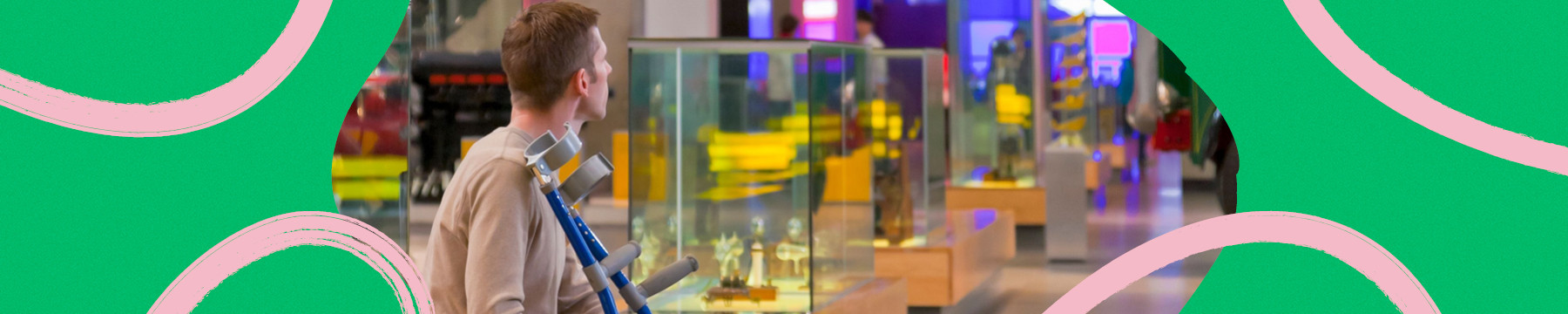 Person sitting down looking at the displays in a museum holding their crutches
