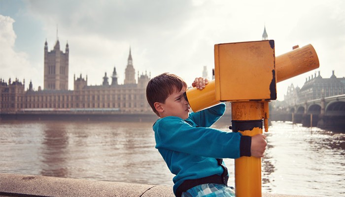 Child looking view a telescope with the Houses of Parliment in the background