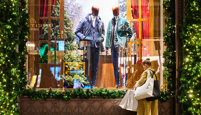 person outside a store window decorated for christmas