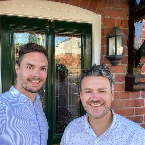 Sam and Dan taking a selfie outside the front of their home.