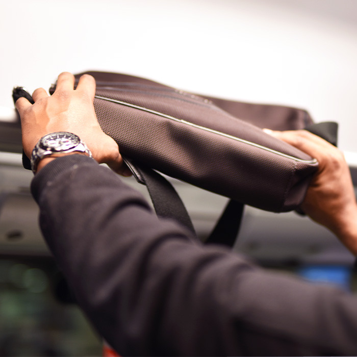passenger putting bag on overhead storage on train