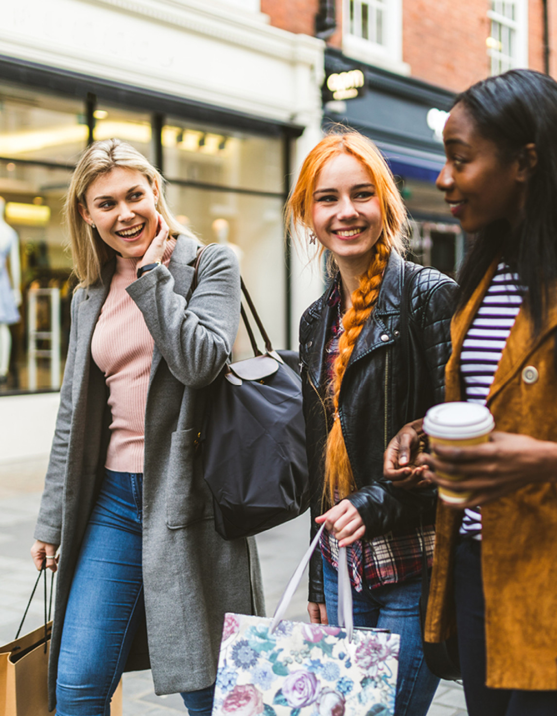 three people smiling with shopping bags